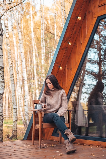 Femme appréciant en journée d'automne sur la terrasse de sa maison