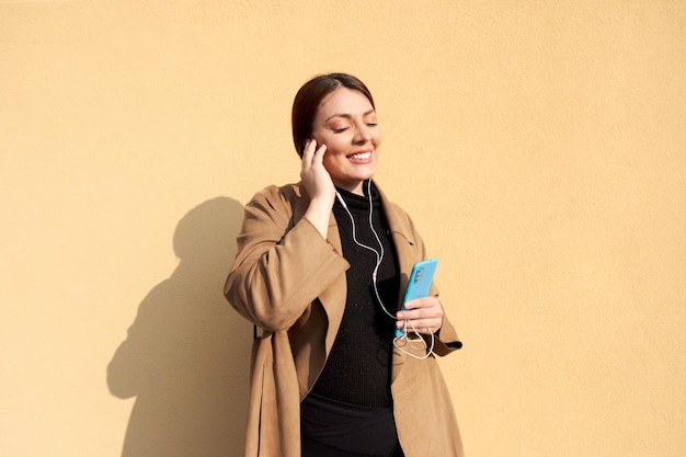 Photo femme appréciant la musique à l'extérieur avec téléphone et écouteurs