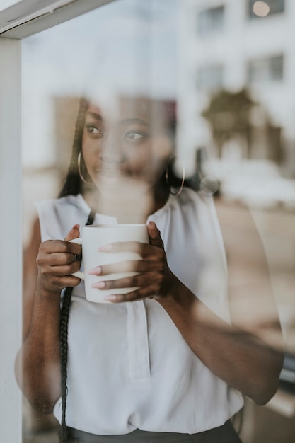 Femme appréciant une tasse de café tout en regardant par la fenêtre