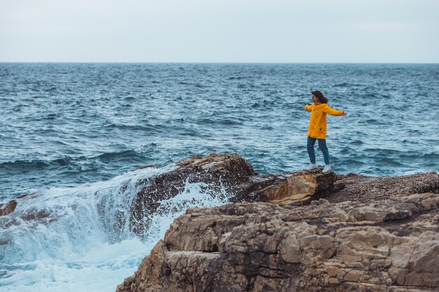 Femme appréciant le temps de tempête en mer bord de mer rocheux