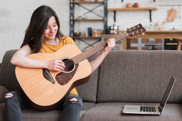 Femme apprenant en ligne à jouer de la guitare