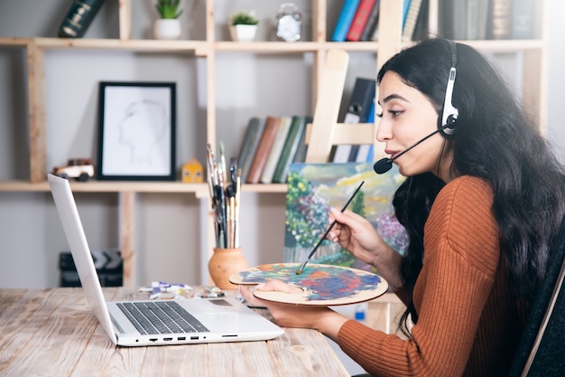 La femme apprend ou travaille à dessiner en ligne à la maison.