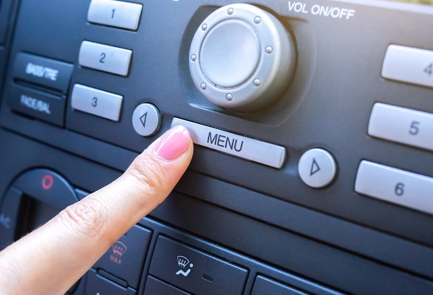 La femme appuie sur le bouton de menu dans la voiture.