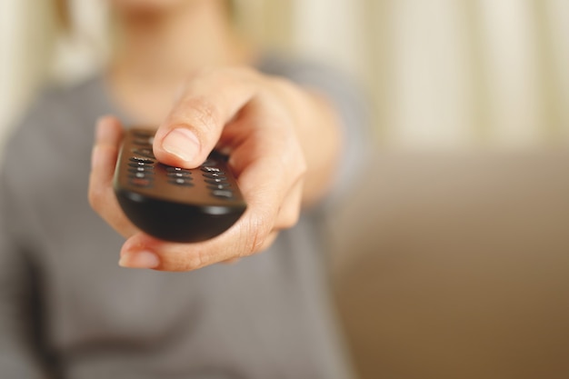 Une femme appuie sur la télécommande de la télévision en ligne à la maison