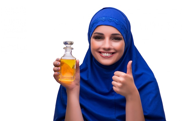 Femme arabe avec une bouteille de parfum isolé sur blanc