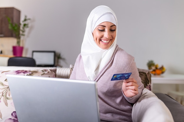 Femme arabe faisant un achat en ligne sur un ordinateur portable. Paiement par carte de crédit. Achats en ligne femme musulmane