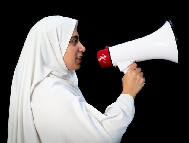 Femme arabe musulmane avec hijab criant par mégaphone appelant au Hajj