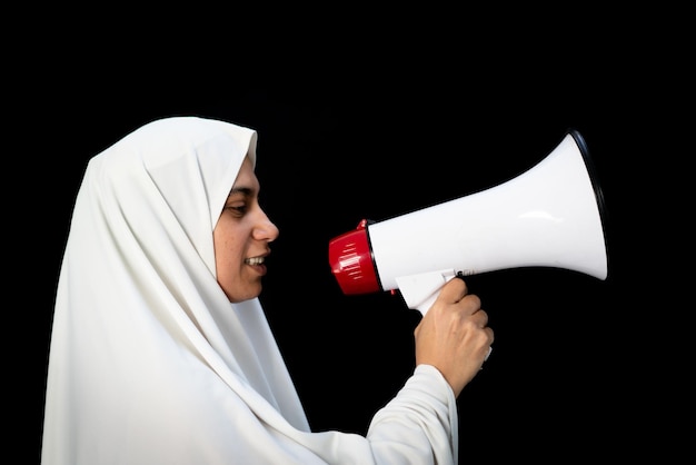Femme arabe musulmane avec hijab criant par mégaphone appelant au Hajj