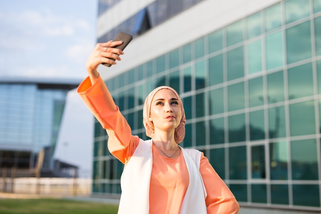 Femme arabe prenant selfie. Belle jeune femme musulmane marche dans la ville.