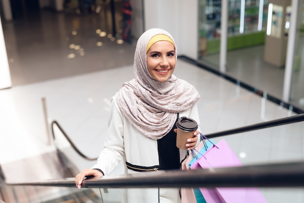 Femme arabe avec une tasse de café debout dans le centre commercial.