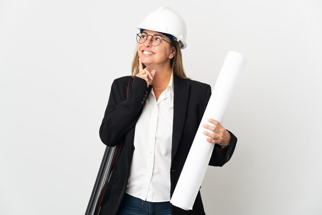 Femme d'architecte d'âge moyen avec casque et tenant des plans isolés