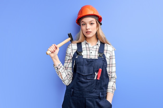 Femme d'architecte confiante tenant un marteau dans les mains prêt à réparer