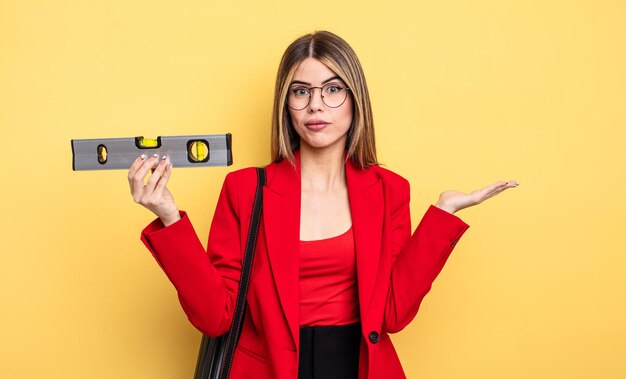 Femme architecte se sentant perplexe et confuse et doutant et tenant un équilibre de niveau