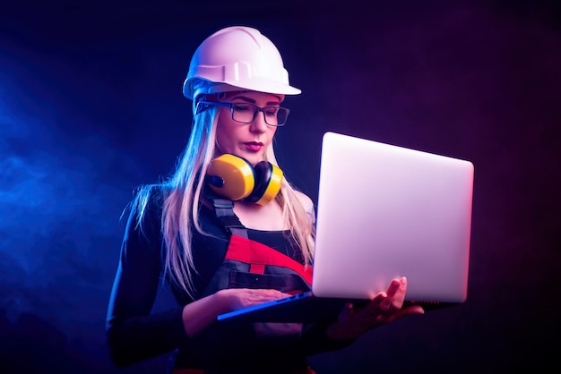 La femme architecte sexy avec un ordinateur portable à lunettes. à la lumière des néons