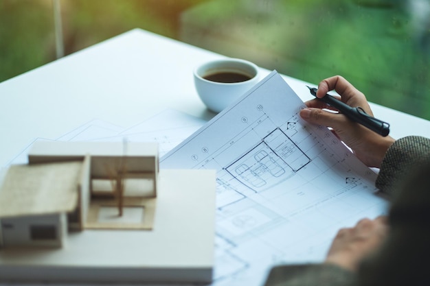 Une femme architecte travaillant sur un modèle de maison d'architecture avec du papier à dessin d'atelier au bureau