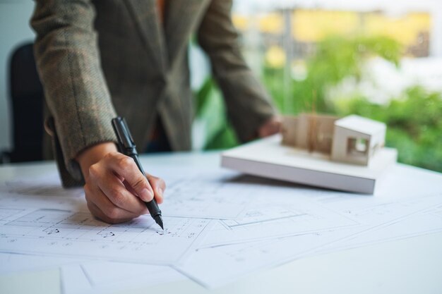 Une femme architecte travaillant sur un modèle de maison d'architecture avec du papier à dessin d'atelier au bureau