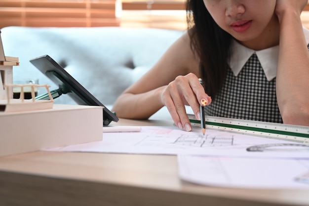 Femme architecte travaillant avec un plan dans le salon.