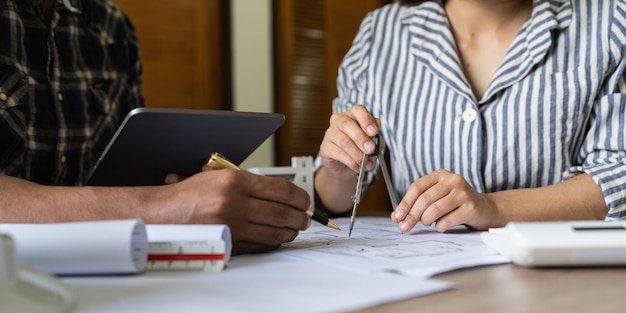 Photo femme architecte travaillant avec des plans pour l'ingénieur de plan architectural esquissant un concept d'énergie verte de projet de construction