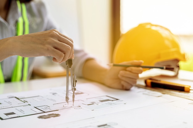 Une femme architecte utilise un rond-point pour dessiner sur les plans de la maison, elle vérifie les plans de la maison qu'elle a conçus avant de les envoyer aux clients, elle conçoit la maison et l'intérieur.