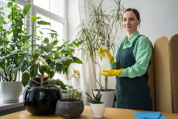 Une femme arrose et pulvérise des plantes domestiques le concept d'un jardin à domicile soins de printemps des plantes à domicile