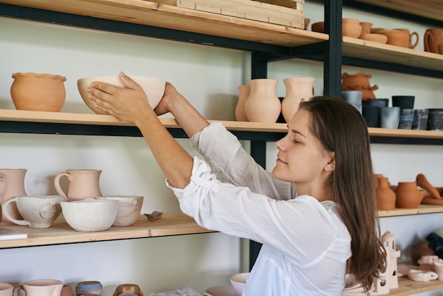 Femme artisan céramiste met sur un support un bol d'argile fait main