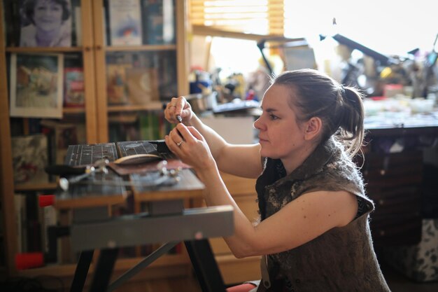 Photo la femme artisan travaille avec la décoration fait la base de métal de cuivre sous l'émail le concept