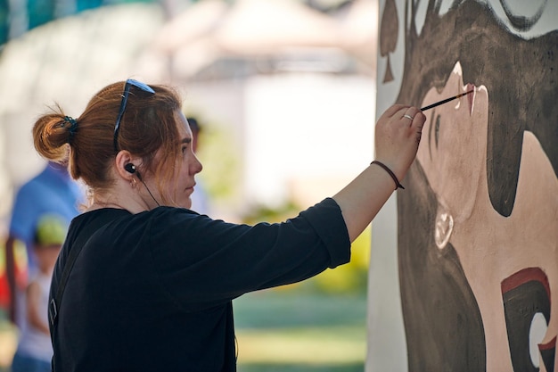 Femme artiste dessine avec un pinceau portrait de fille surréaliste sur toile blanche à la peinture d'art