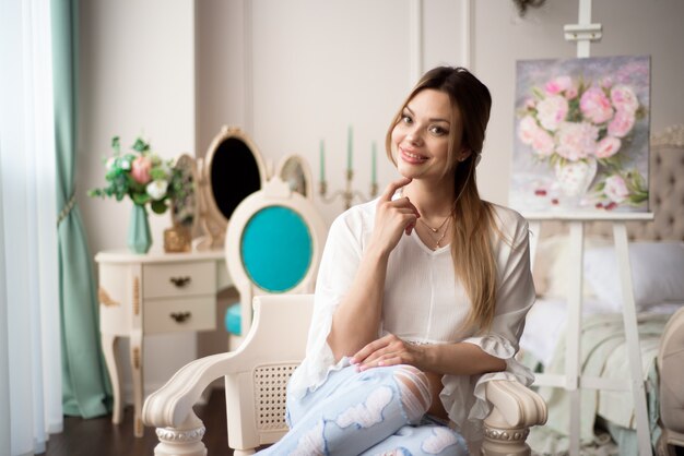 Une femme artiste avec une photo sur un chevalet à la maison. Le peintre peint des peintures à l'huile.