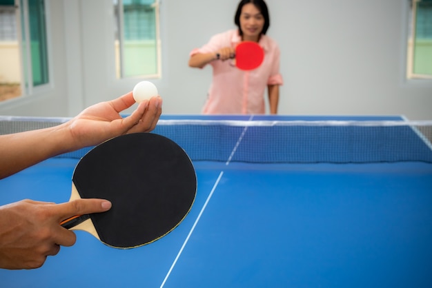 Une femme asiatique adulte attend pour commencer à jouer au tennis de table ou au ping-pong à l'intérieur. Loisirs avec compétition dans les jeux de sport à la maison, Loisirs ou exercice rester à la maison avec la famille en Thaïlande