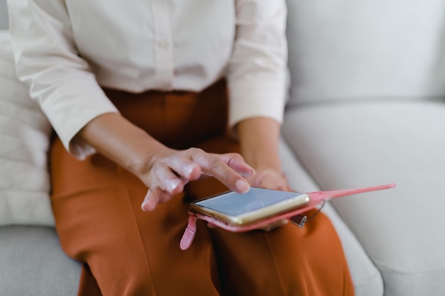 Femme asiatique d'âge moyen tenant un téléphone portable femme âgée avec téléphone intelligent femme âgée utilisant un smartphone à la maison avec concept technologique