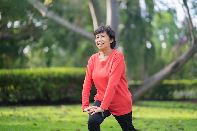 Femme asiatique âgée se réchauffant le corps avant de faire de l'exercice Vieille femme s'étirant avant de faire du jogging dans le jardin