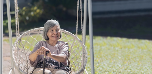 Femme asiatique âgée se reposant sur une balançoire dans l'arrière-cour