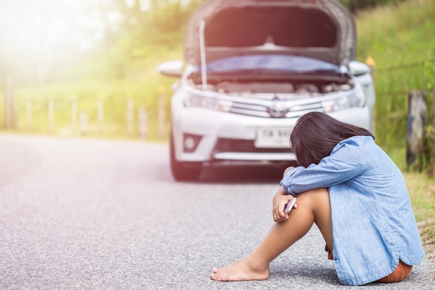 Femme asiatique à l&#39;aide de smartphone devant sa voiture cassée sur la route