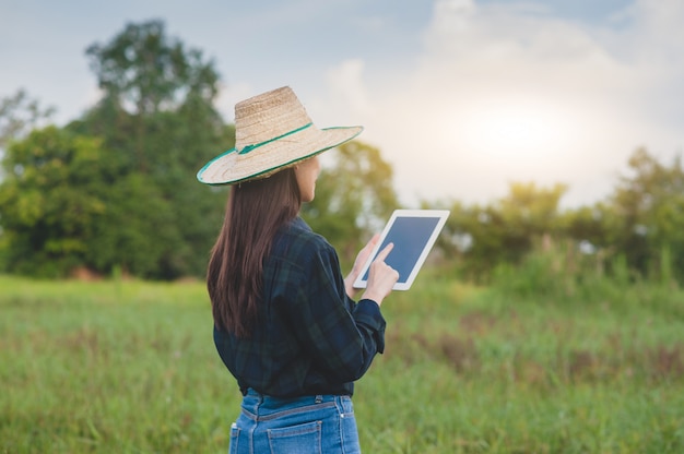 Femme asiatique à l'aide d'une tablette sur un champ agricole