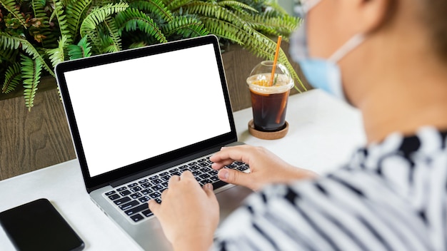 Photo femme asiatique à l'aide et en tapant sur un ordinateur portable avec écran blanc isolé