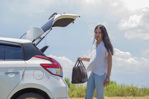 Femme asiatique allant en vacances chargeant son coffre de voiture avec des valises de voyage