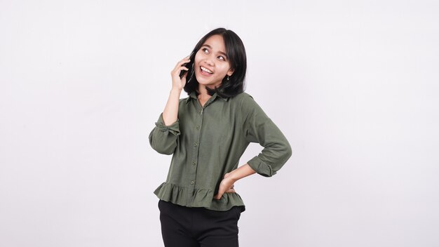 Femme asiatique appelant et sourit debout sur un mur blanc