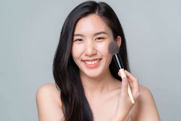 Femme asiatique appliquant du sérum hyaluronique sur son visage avec une pipette