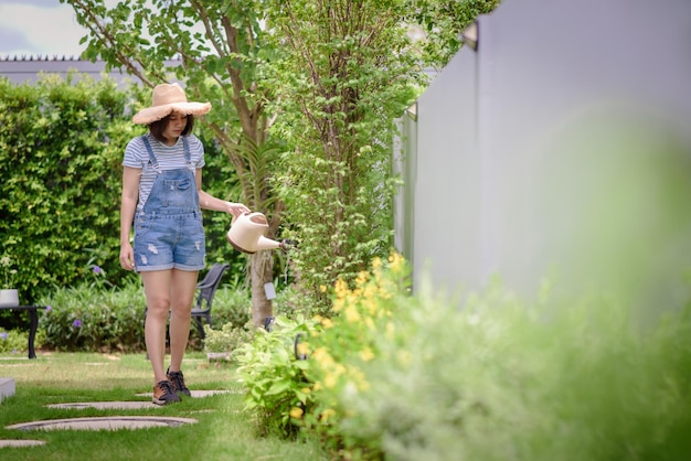 Une femme asiatique arrose des plantes dans le jardin