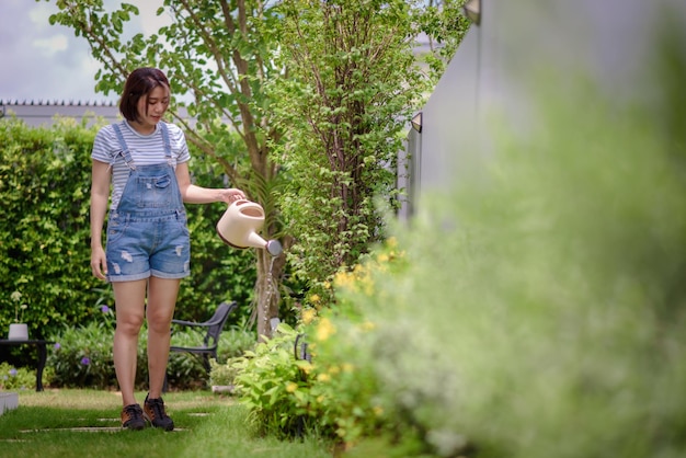 Une femme asiatique arrose des plantes dans le jardin