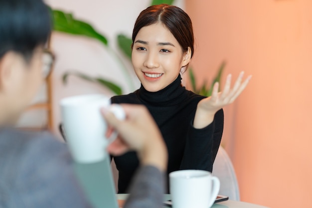 Femme asiatique assise et bavardant avec des collègues dans le café après le travail