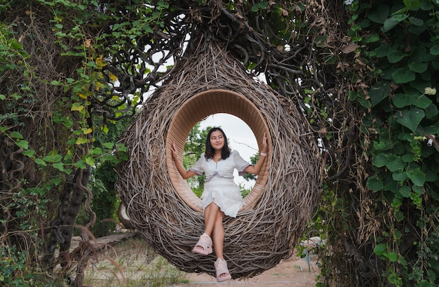 Femme asiatique assise dans un nid d'oiseau en bois dans une forêt d'arbres verts à l'écart heureux de la nature