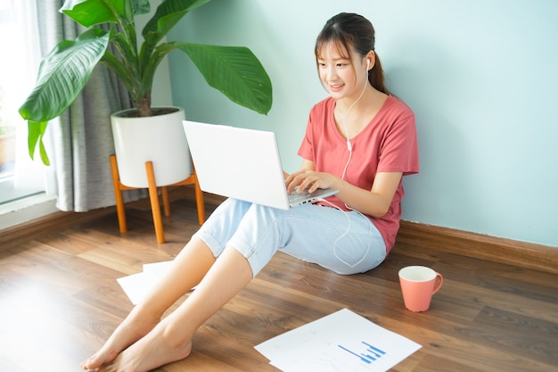 Femme Asiatique Assise Sur Le Sol Pendant Qu'elle Travaille à Domicile