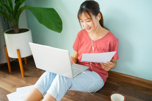 Femme asiatique assise sur le sol pendant qu'elle travaille à domicile