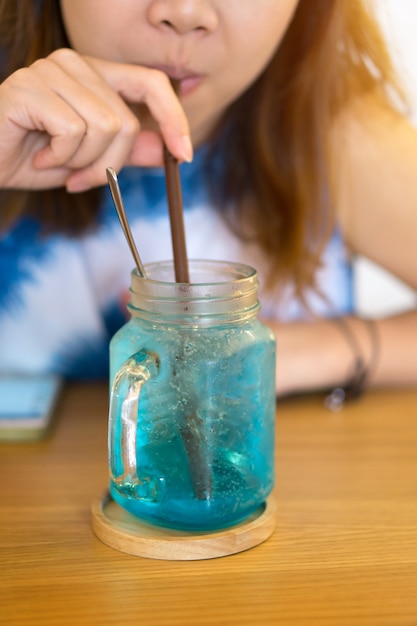 Une femme asiatique assise et suce le jus sucré du tube.