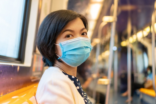 Femme asiatique au masque pour la protection contre les coronavirus dans le train de banlieue se rendant au travail