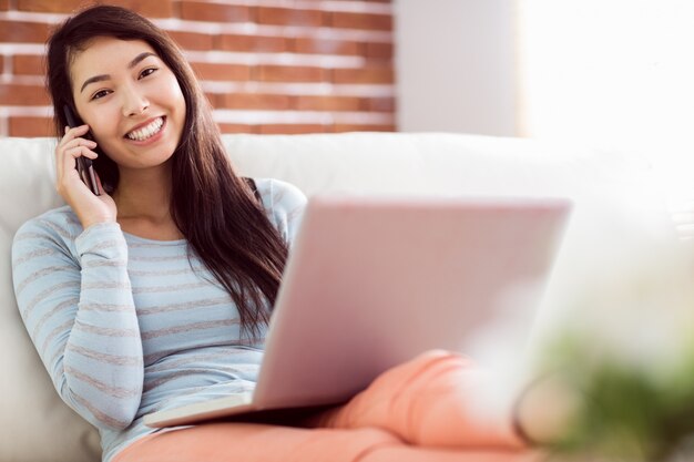 Femme asiatique au téléphone en utilisant un ordinateur portable