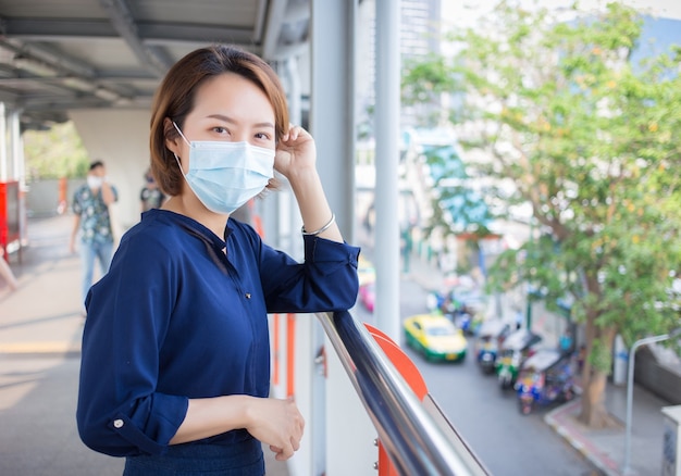 Une femme asiatique aux cheveux courts porte un masque médical comme nouveau mode de vie normal.