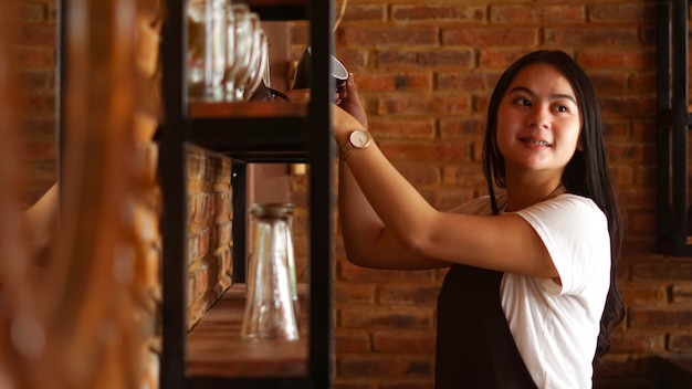 Femme asiatique barista organisant des verres au café