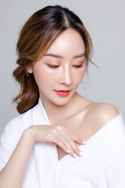 Femme asiatique avec un beau visage et une peau fraîche et propre parfaite Portrait d'un modèle féminin avec un maquillage naturel et des yeux étincelants sur fond gris isolé